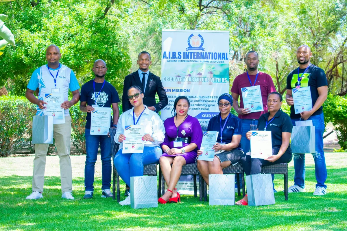 Participants holding their AIBS certificates of attendance outdoors beside the AIBS banner